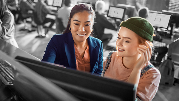 woman helping other woman with computer