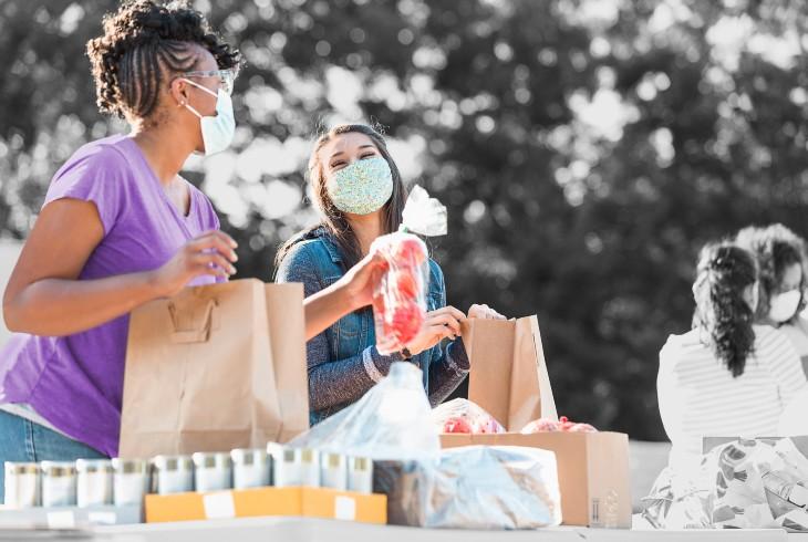 Masked women prepare food bags for food pantry